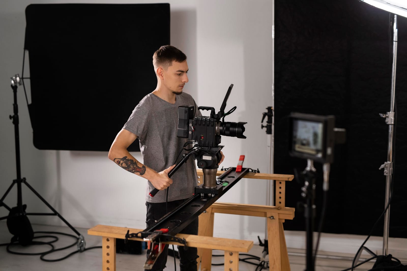 Operador posiciona uma câmera de cinema sobre slider em um estúdio com fundo preto.